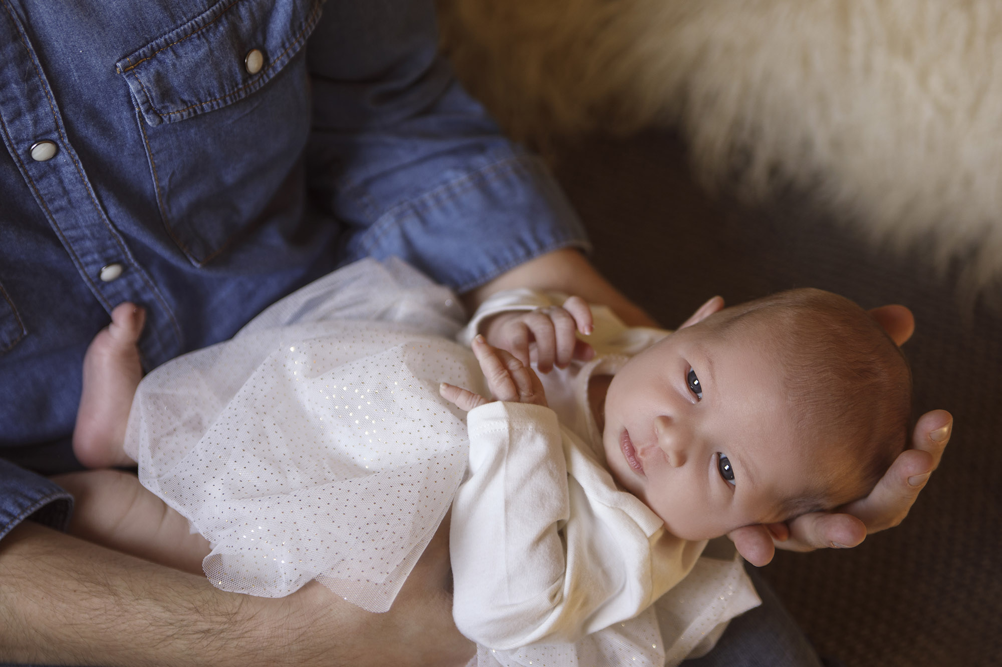 Man holding an infant in white dress