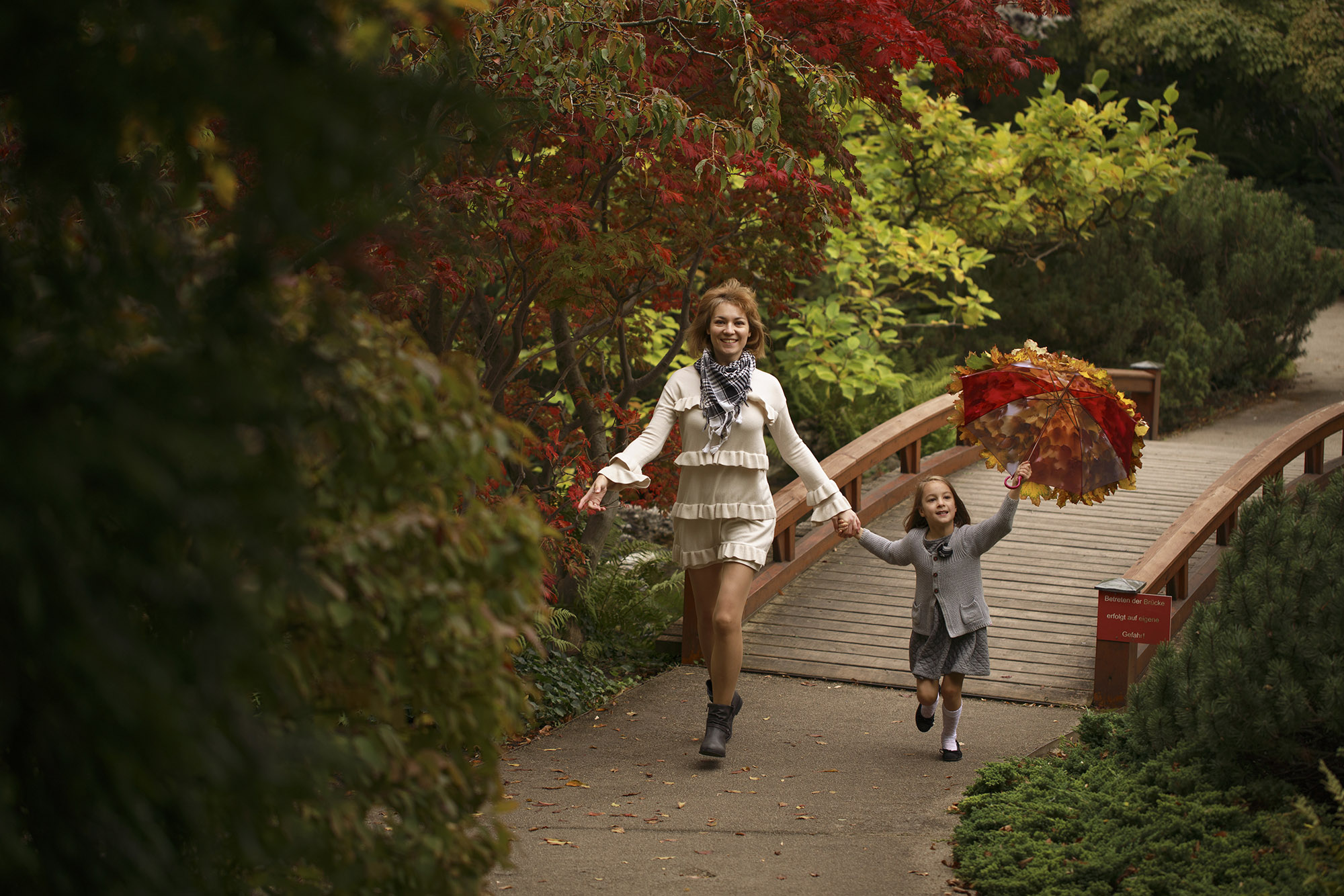 Mother and her daughter with an umbrella covered in leaves in Türkenschanzpark