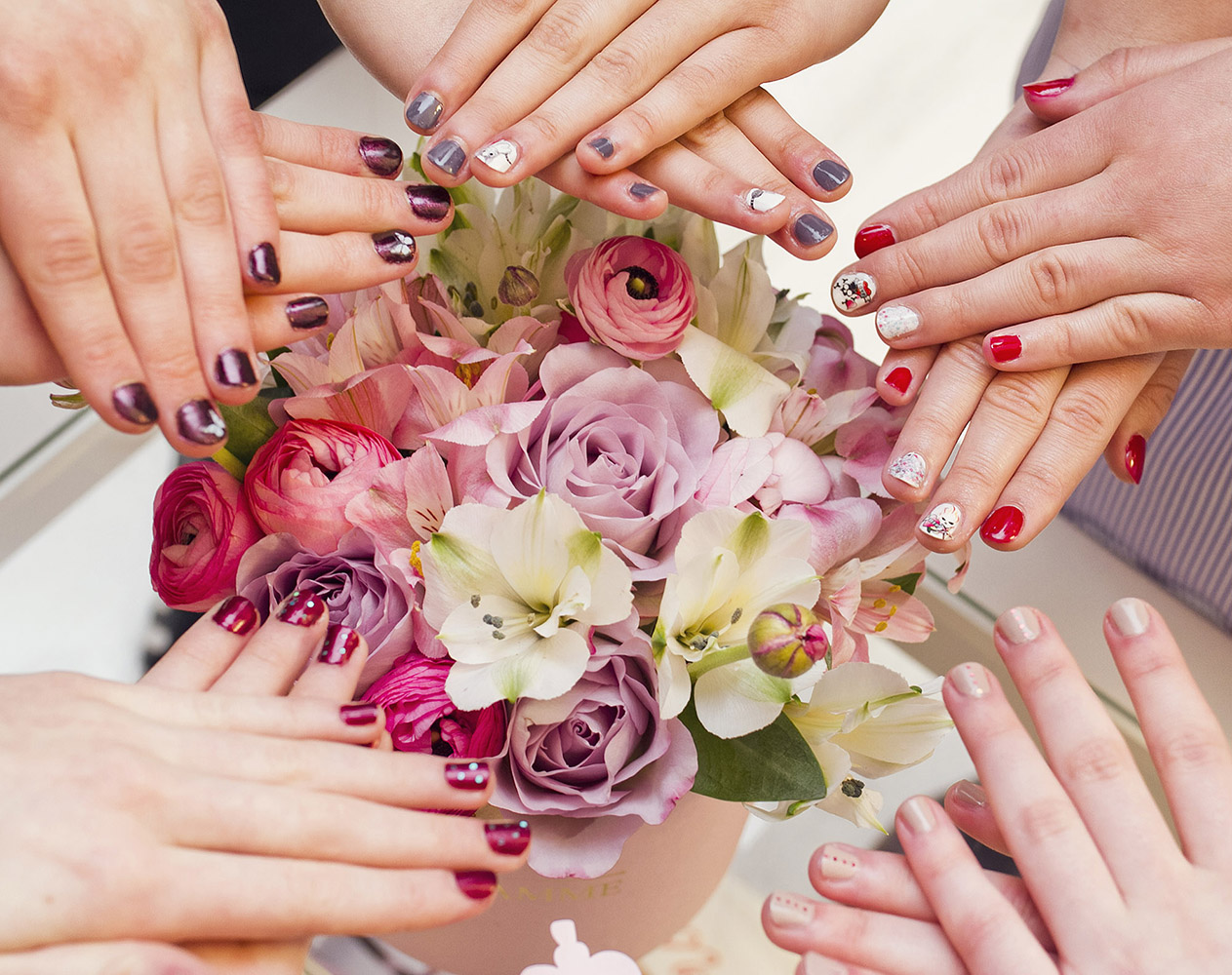 Hands with painted nails with flowers on the background