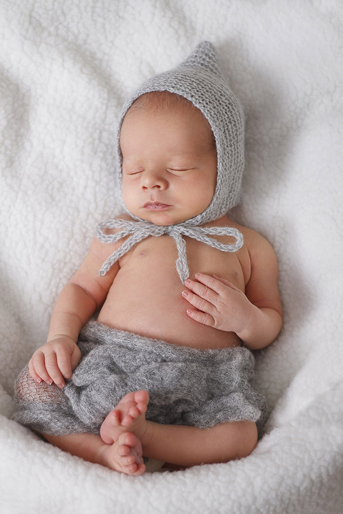 Sleeping infant in knit cap on grey blanket