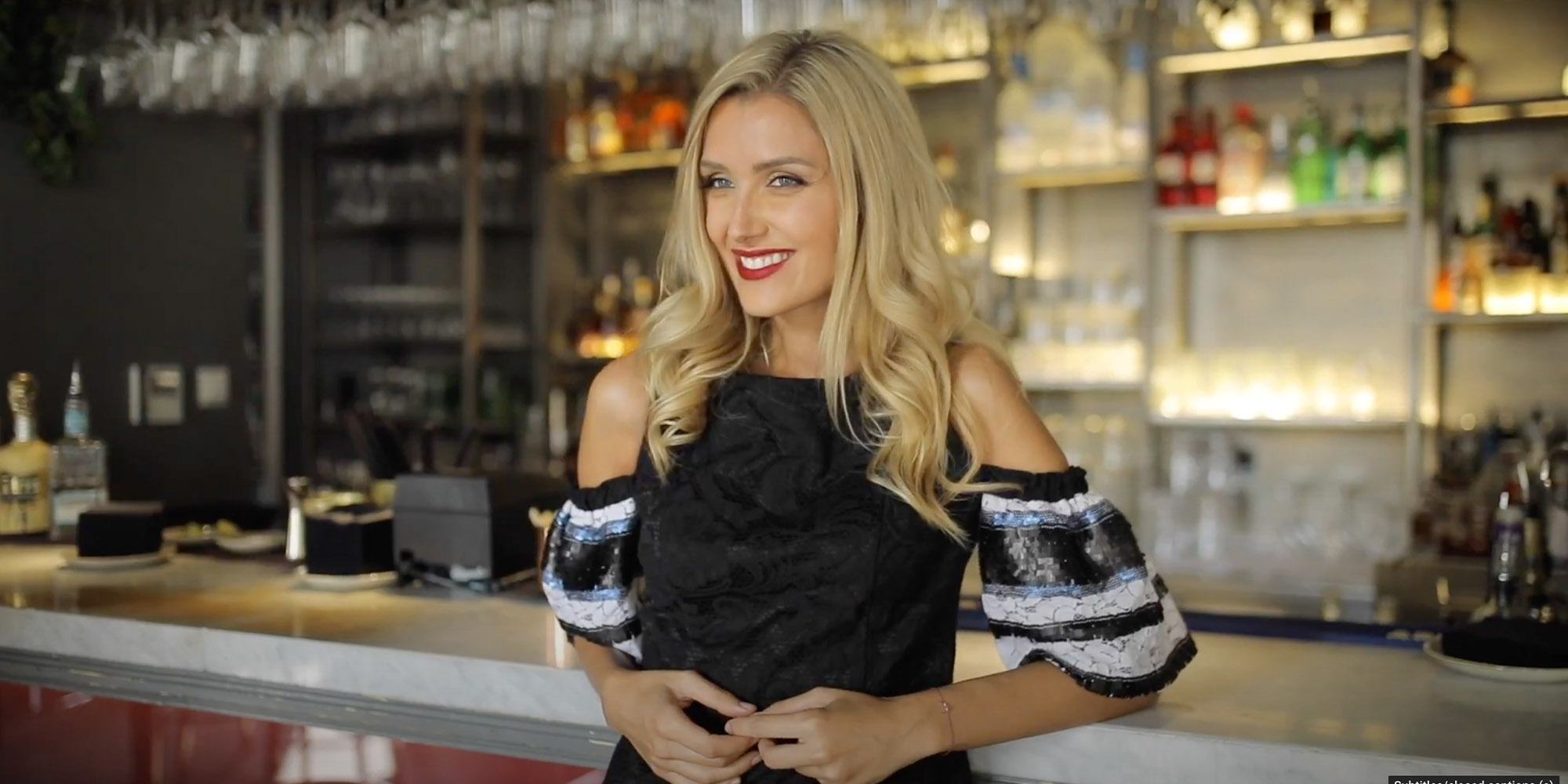 Smiling woman in evening dress next to a bar