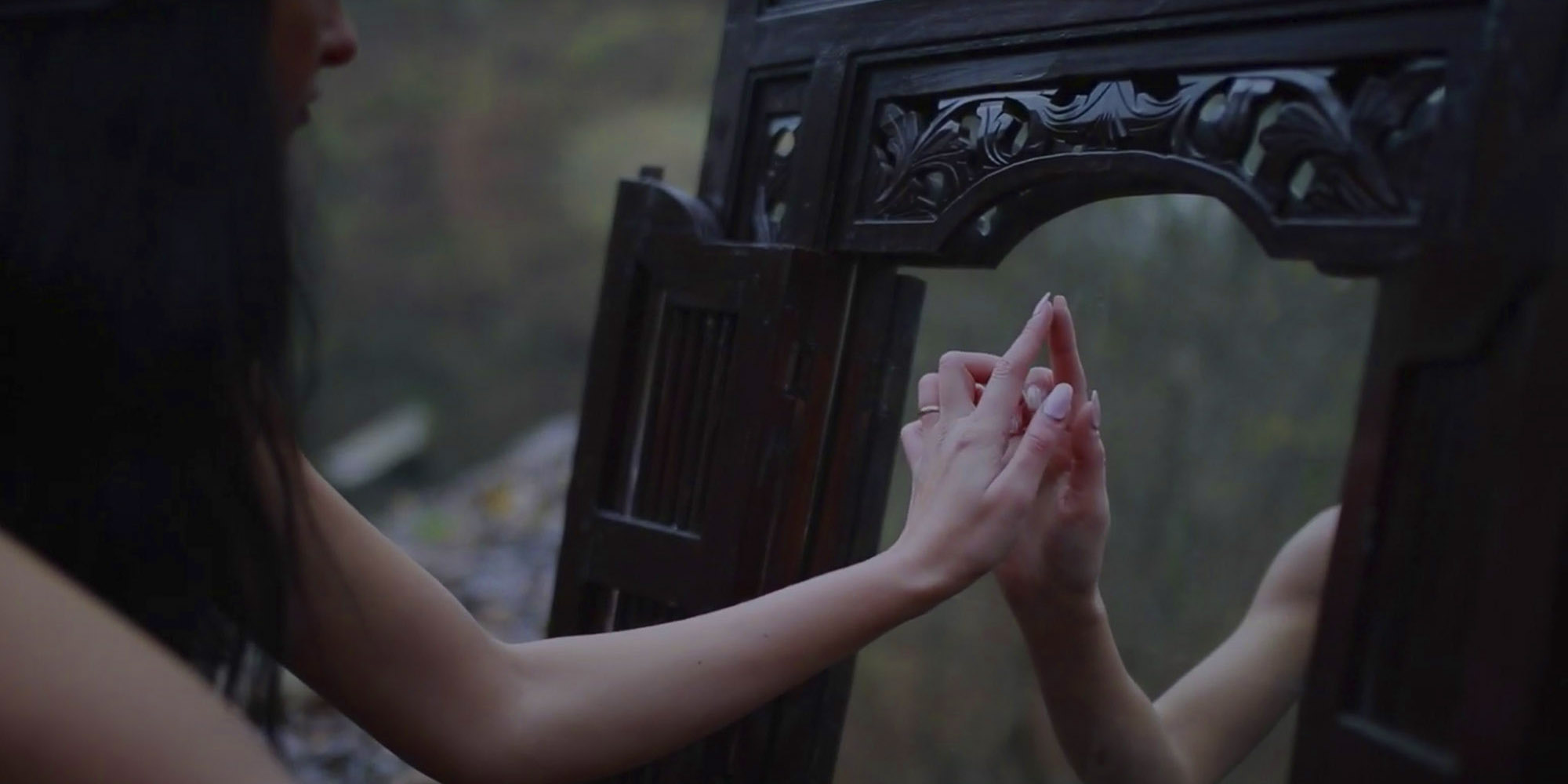 Girl is touching a mirror in woods